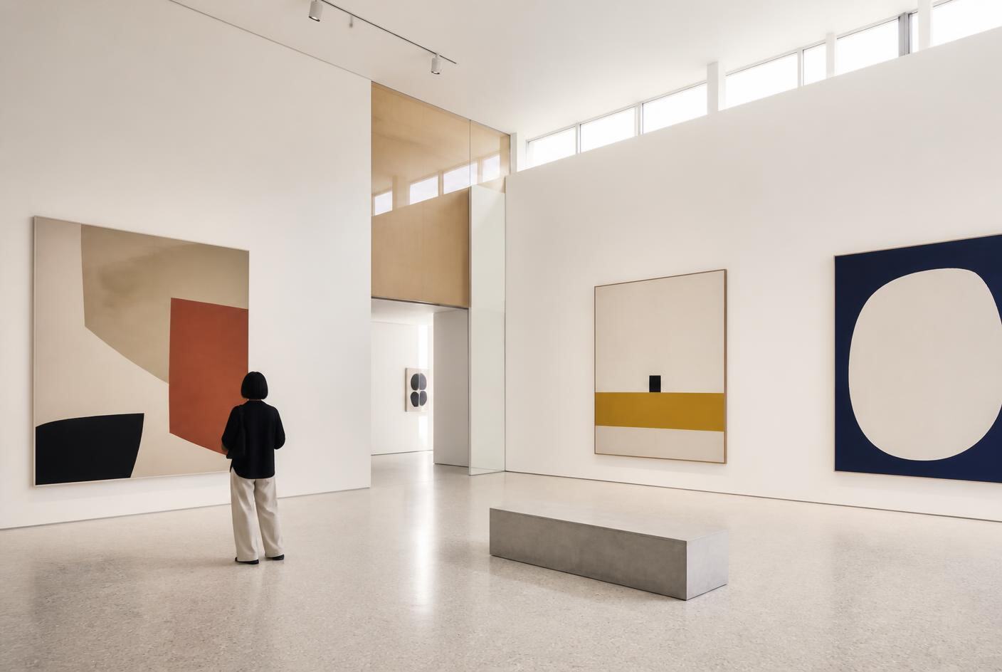 Bright contemporary gallery interior with abstract paintings and a single visitor