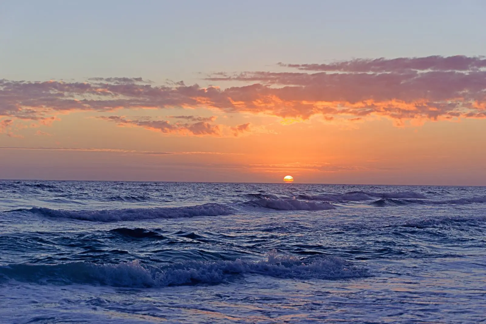 Sunset over the Gulf of Mexico with the Naples Pier silhouetted against orange sky