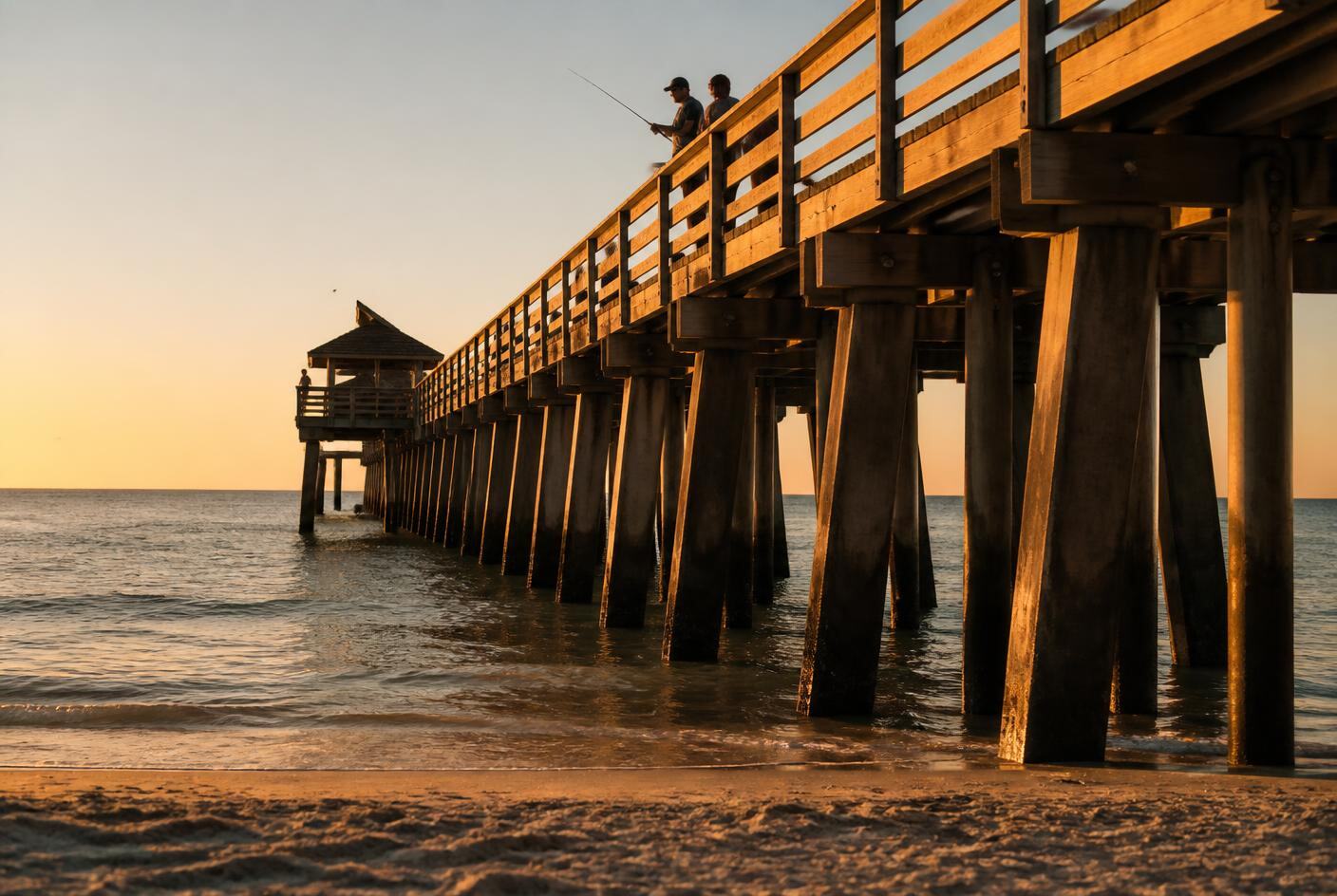 Naples Pier pilings and deck lit by warm golden hour light above calm Gulf water