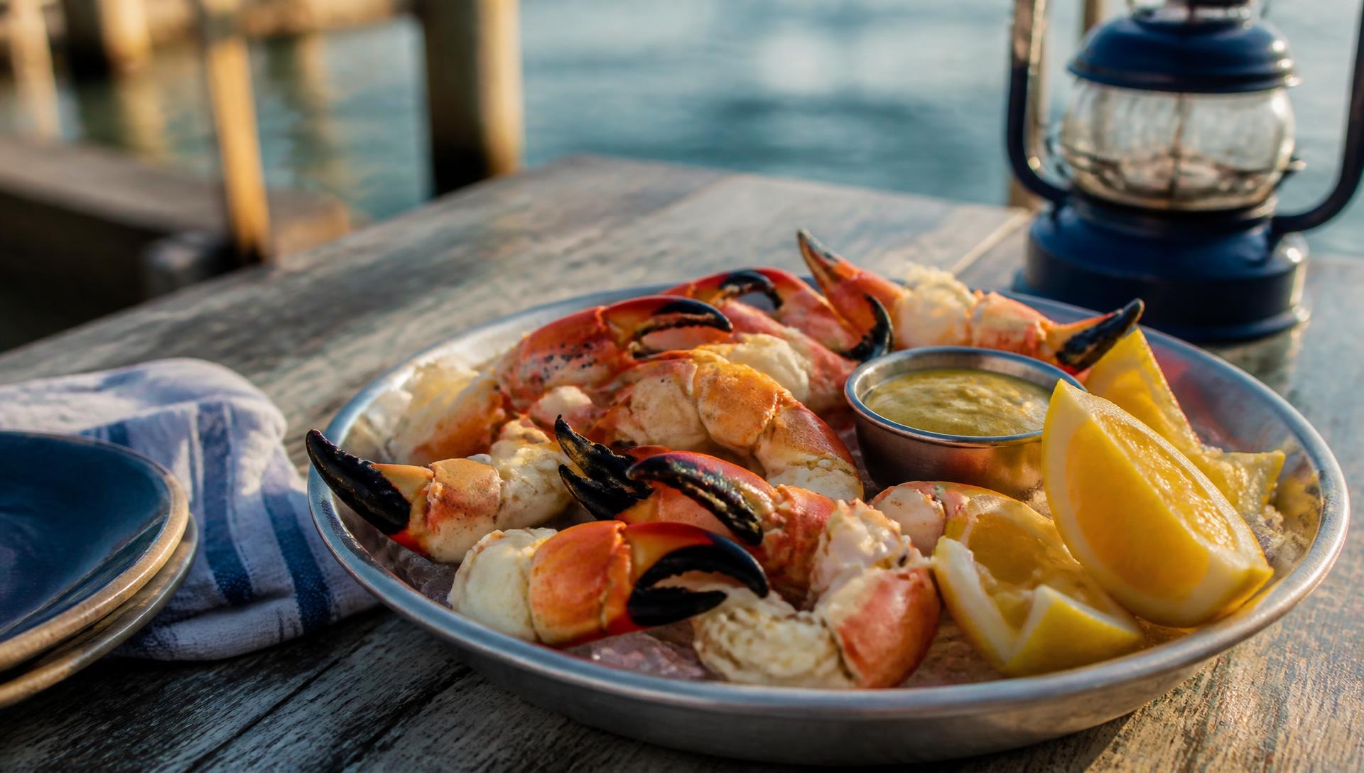 Platter of chilled Florida stone crab claws on ice with lemon and mustard sauce on a dockside table